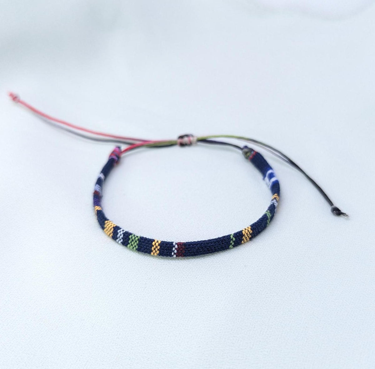 Navy woven bracelet with a multicolour pattern and pink and black adjustable cords