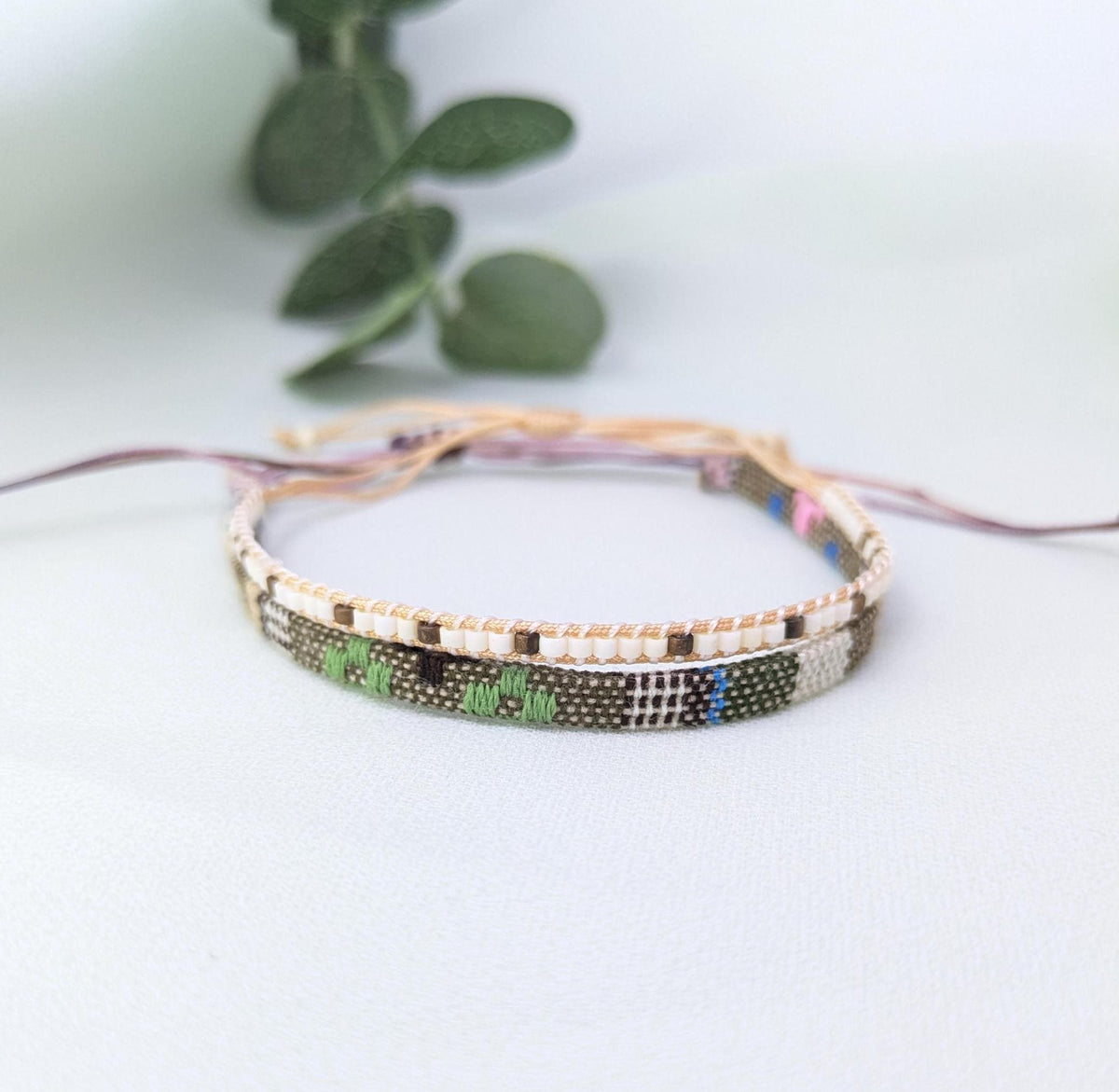 Cream, green and brown patterned woven bracelet with pale pink adjustable cords