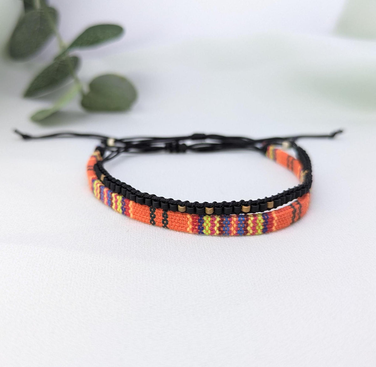 Orange, red and black patterned woven bracelet with black sliding knot cords