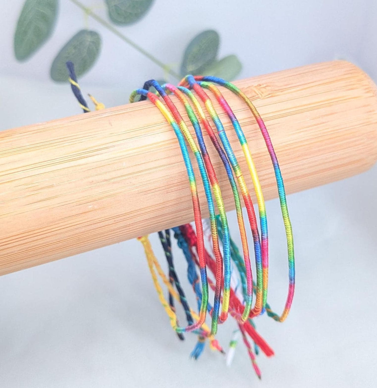 Handmade rainbow string bracelet with an adjustable fit, shown in several colours